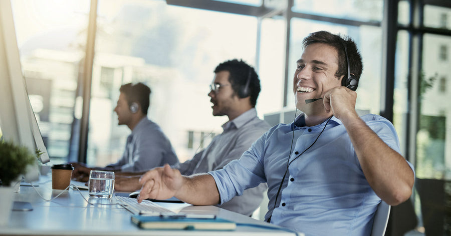 Agentes de atención al cliente utilizando auriculares con micrófono en un moderno centro de trabajo, representando el uso de telefonía IP para mejorar la comunicación